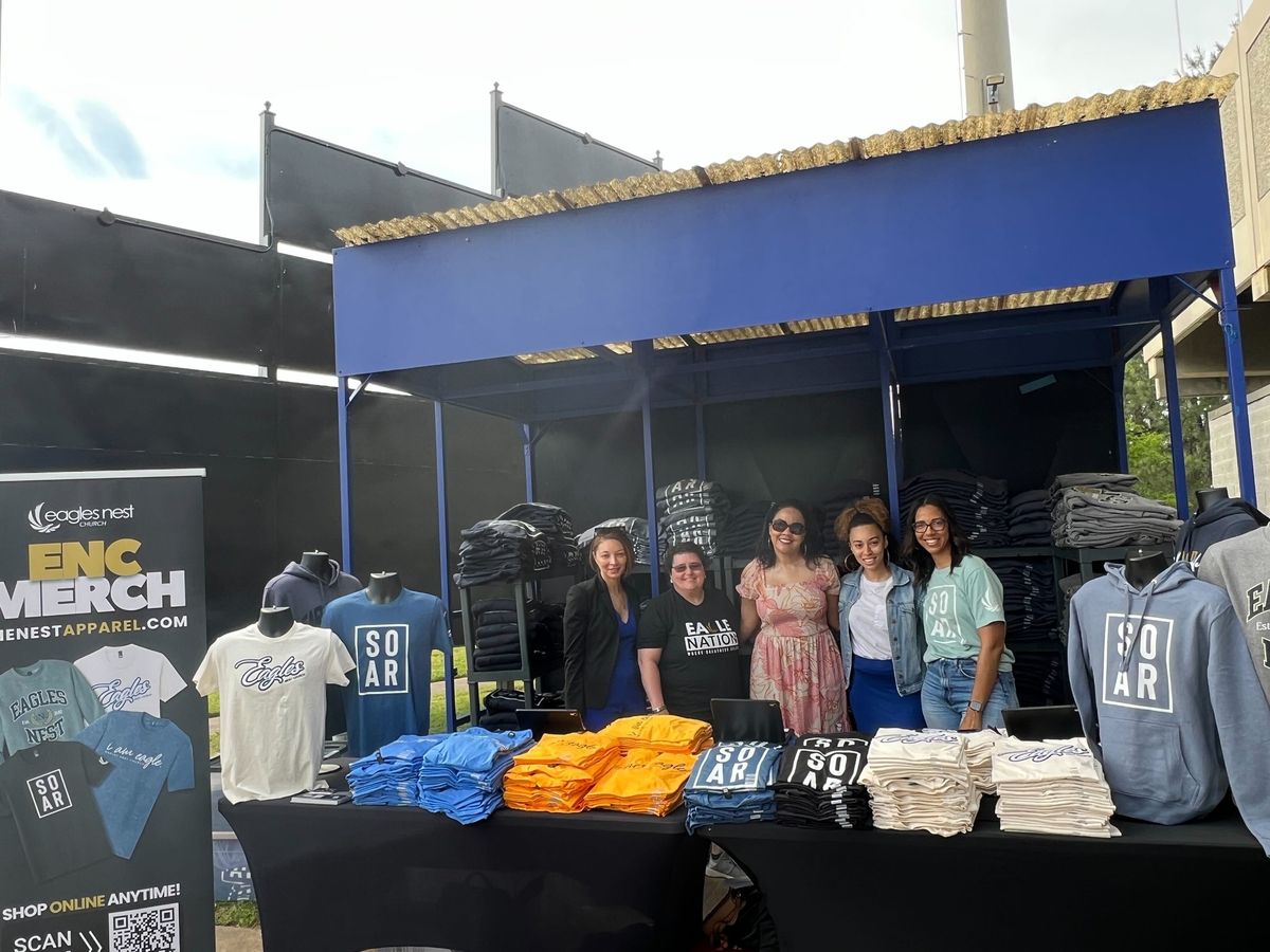 Eagles Nest Church team at their outdoor merch booth with stacks of folded tees