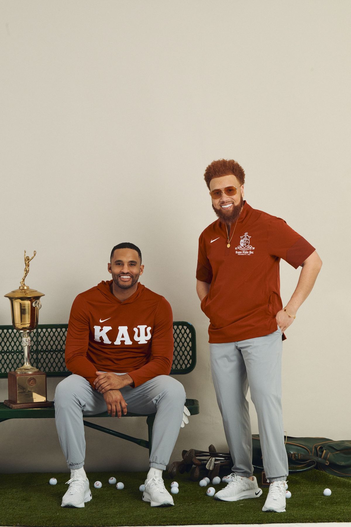 Two men in custom Kappa Alpha Psi golf apparel posing beside a trophy