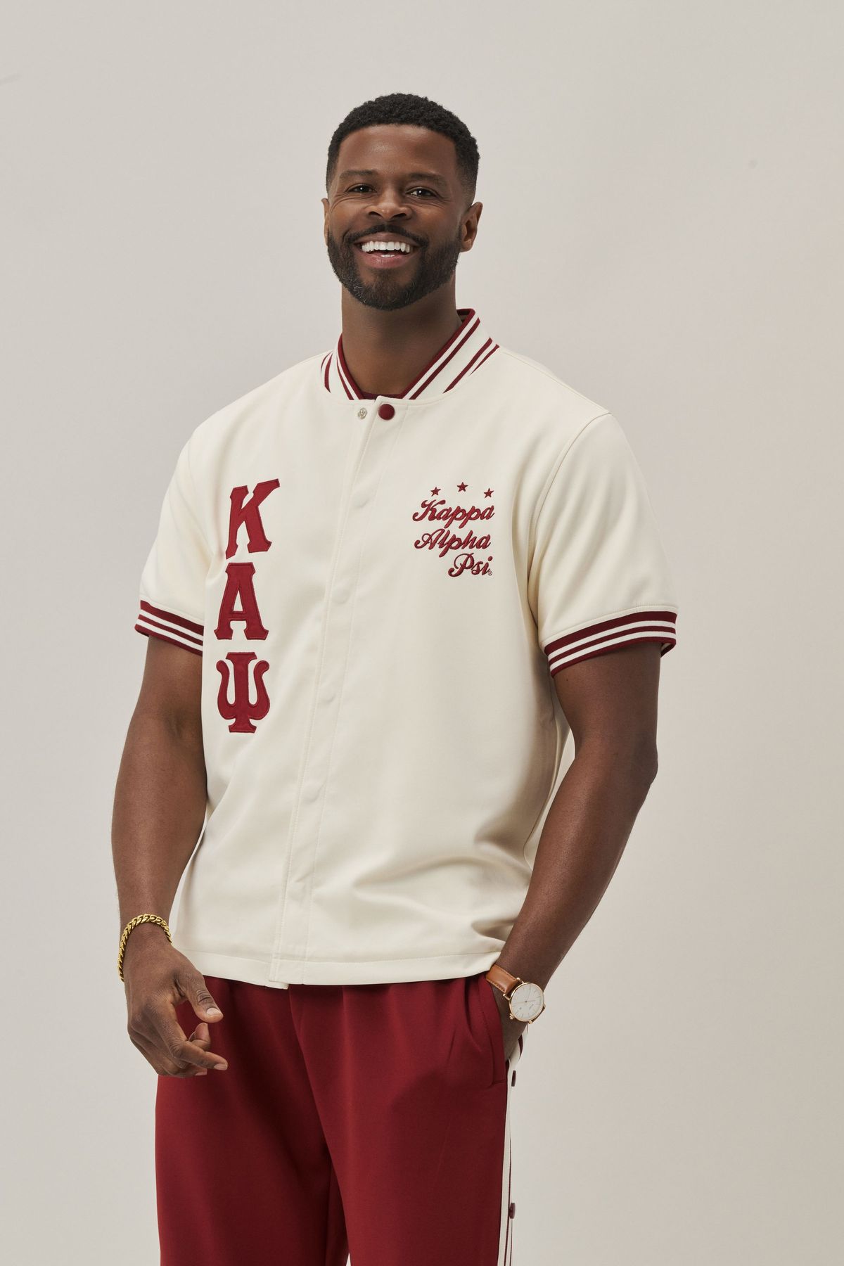 Man in a cream Kappa Alpha Psi varsity-style shirt