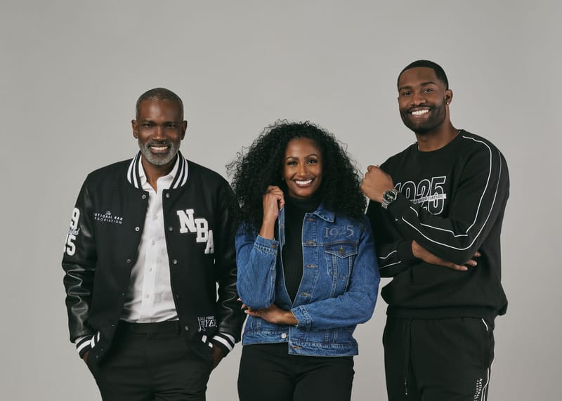 Three people modeling black National Bar Association varsity apparel in a studio