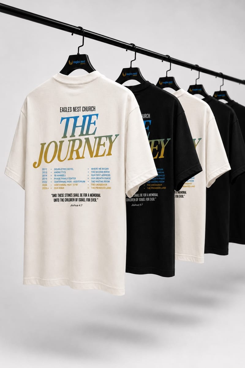 Finished custom tees in cream and black hanging on a garment rack
