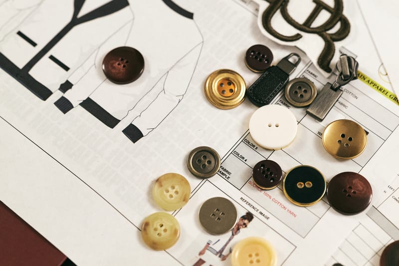 Button and trim options arranged over a jacket design sketch
