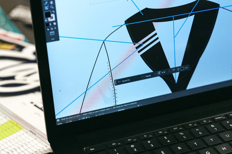 Laptop screen showing an apparel logo being refined in vector design software